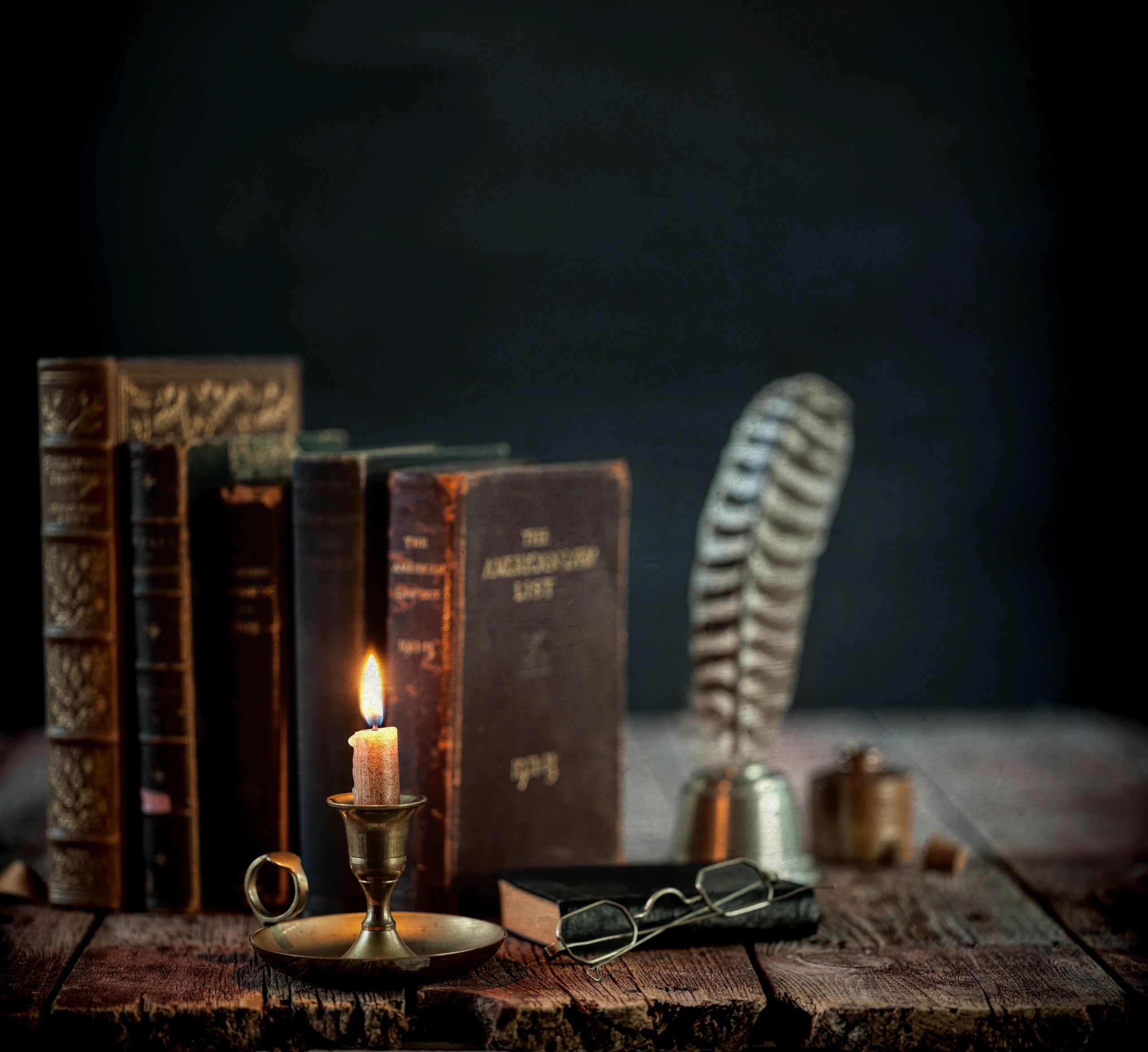 Vintage books and candle on a dark wooden desk