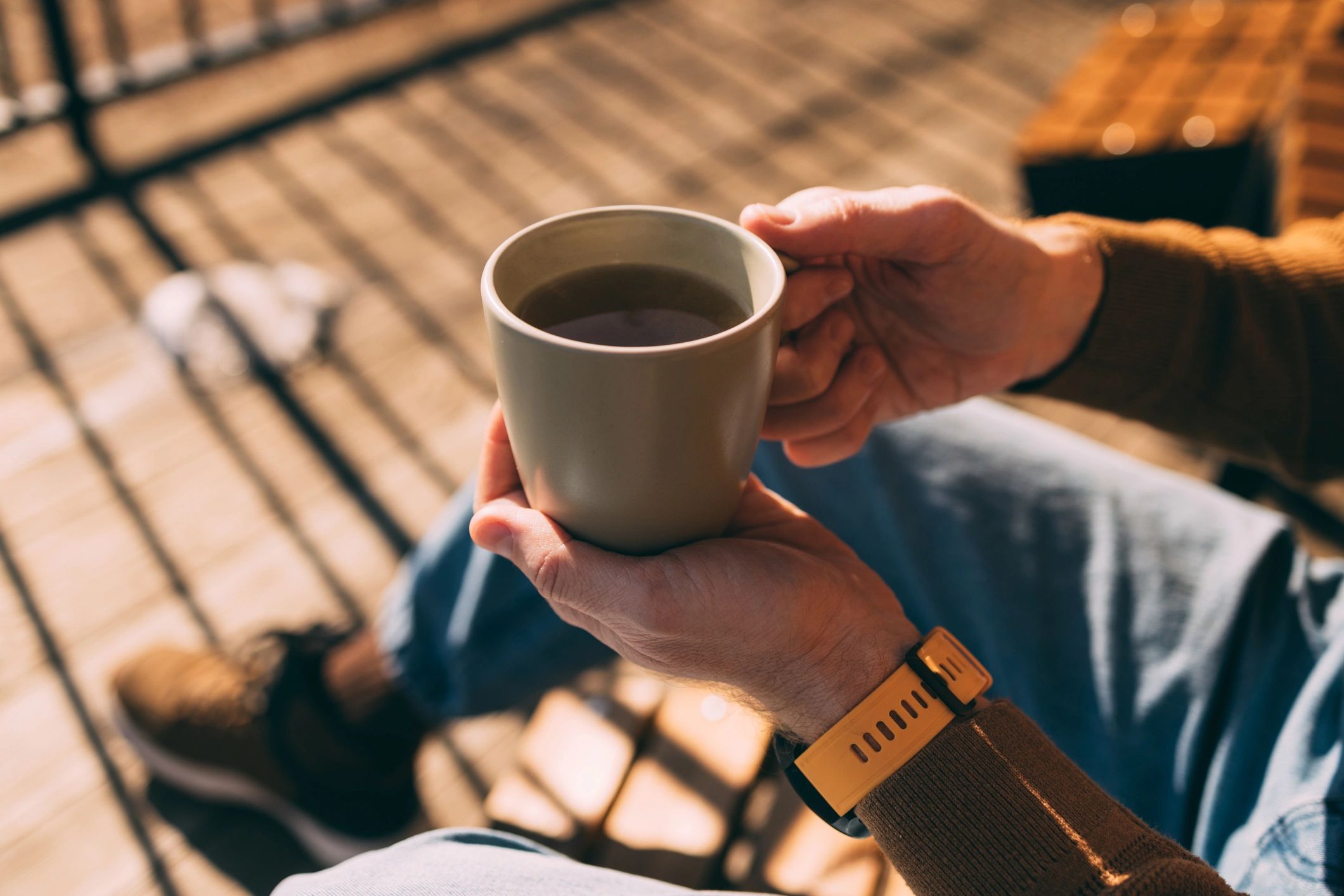 Hands holding a warm mug outdoors, symbolizing comfort and self-care