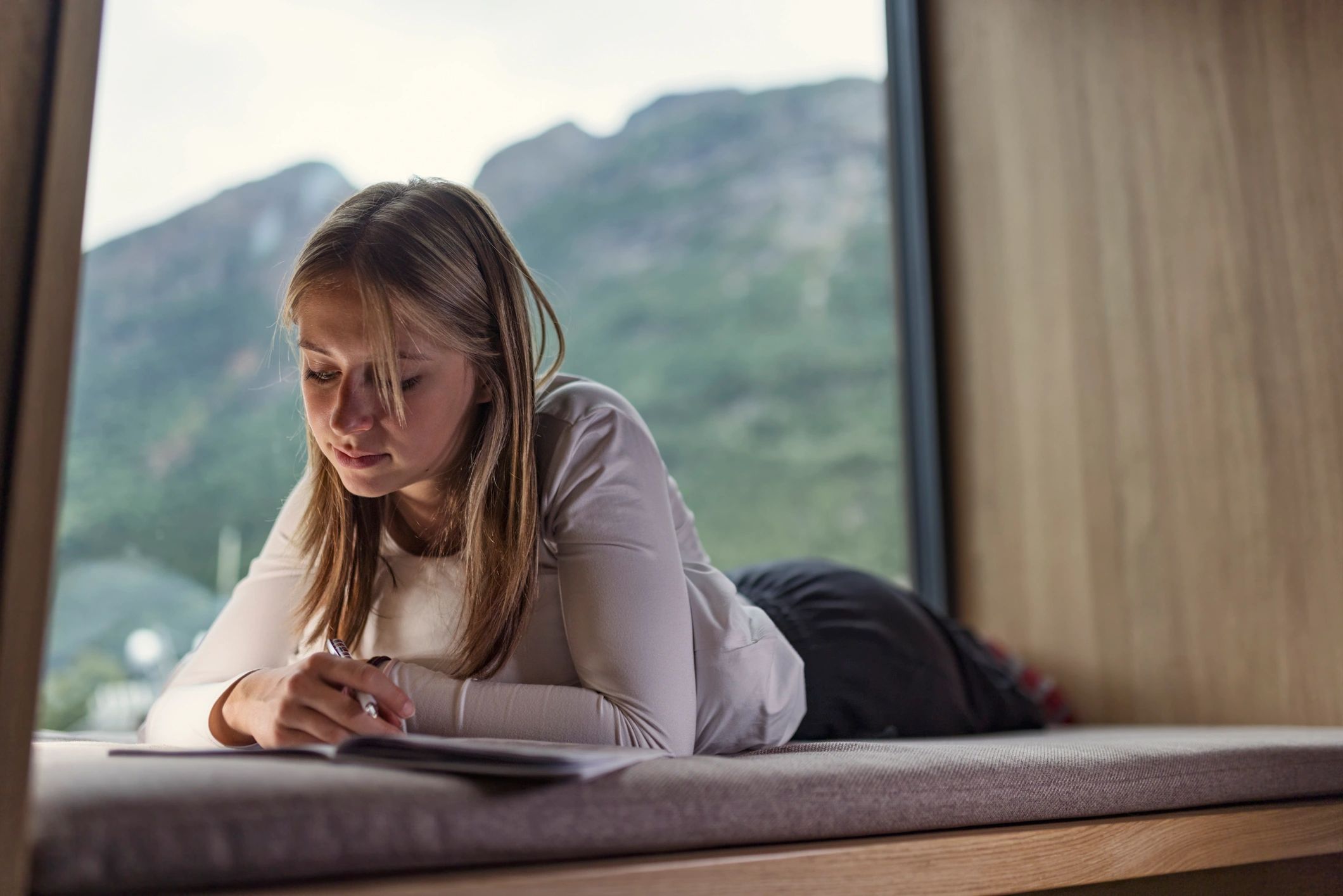 Person journaling by a window, reflecting and writing
