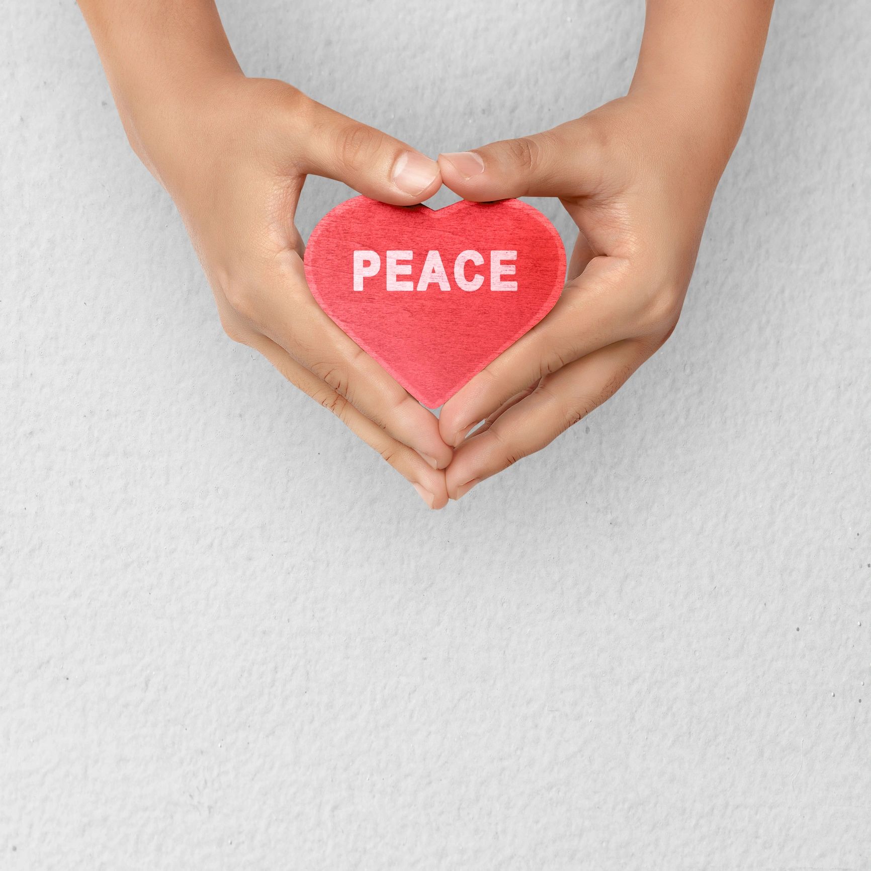 Hands holding a heart with the word “peace,” representing compassion and support